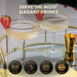 Load image into Gallery viewer, Champagne poured into ribbed coupe glasses with strawberry garnish beside gold cocktail shaker.