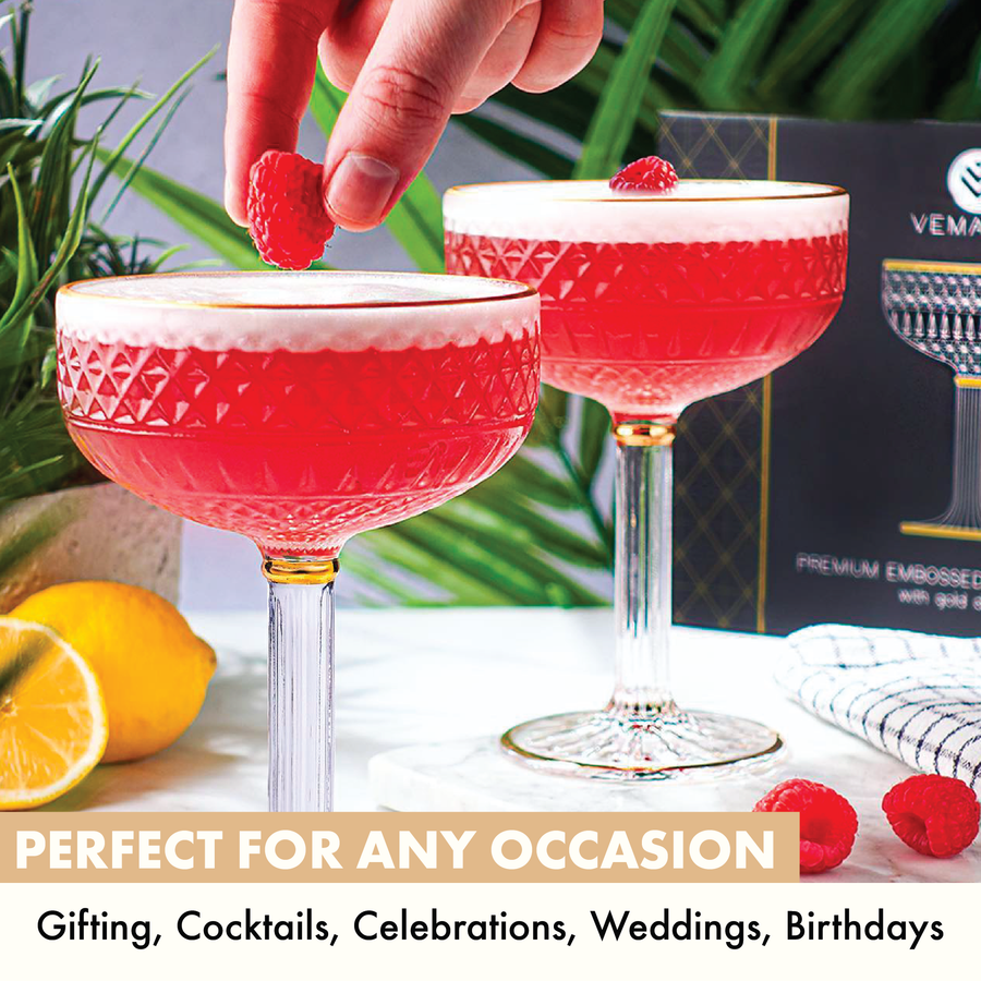 Raspberry cocktail being garnished in coupe cocktail glasses with gold rim, perfect for occasions