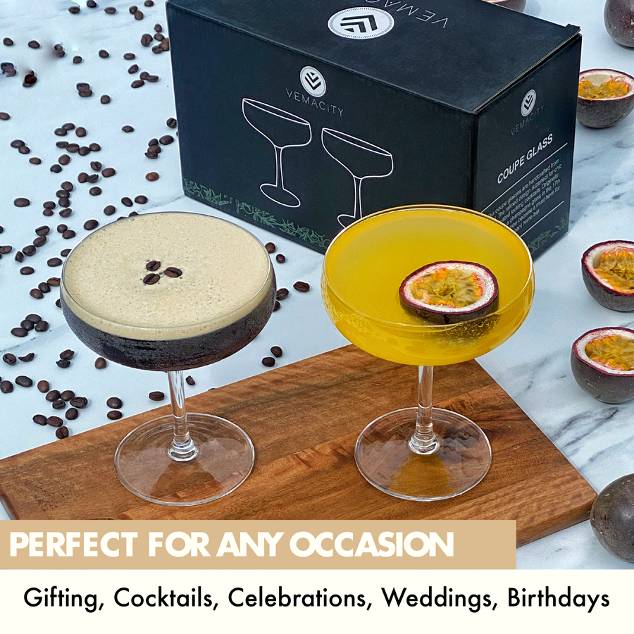 Set of 2 Vemacity crystal coupe glasses with espresso martini and passionfruit cocktail, gift box in background, perfect for celebrations.