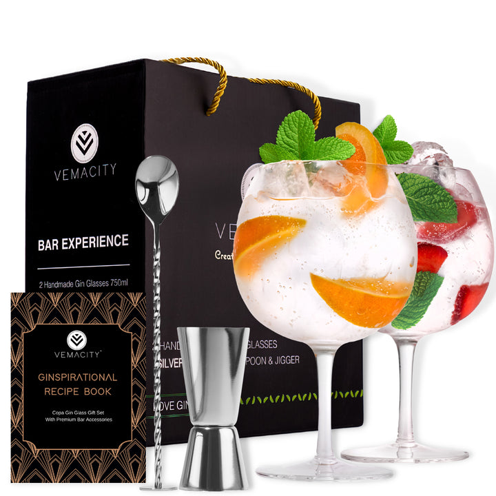 A set of handcrafted crystal gin glasses with silver bar accessories including a bar spoon, shot measure, and a recipe e-book, presented in a black gift box with gold accents.