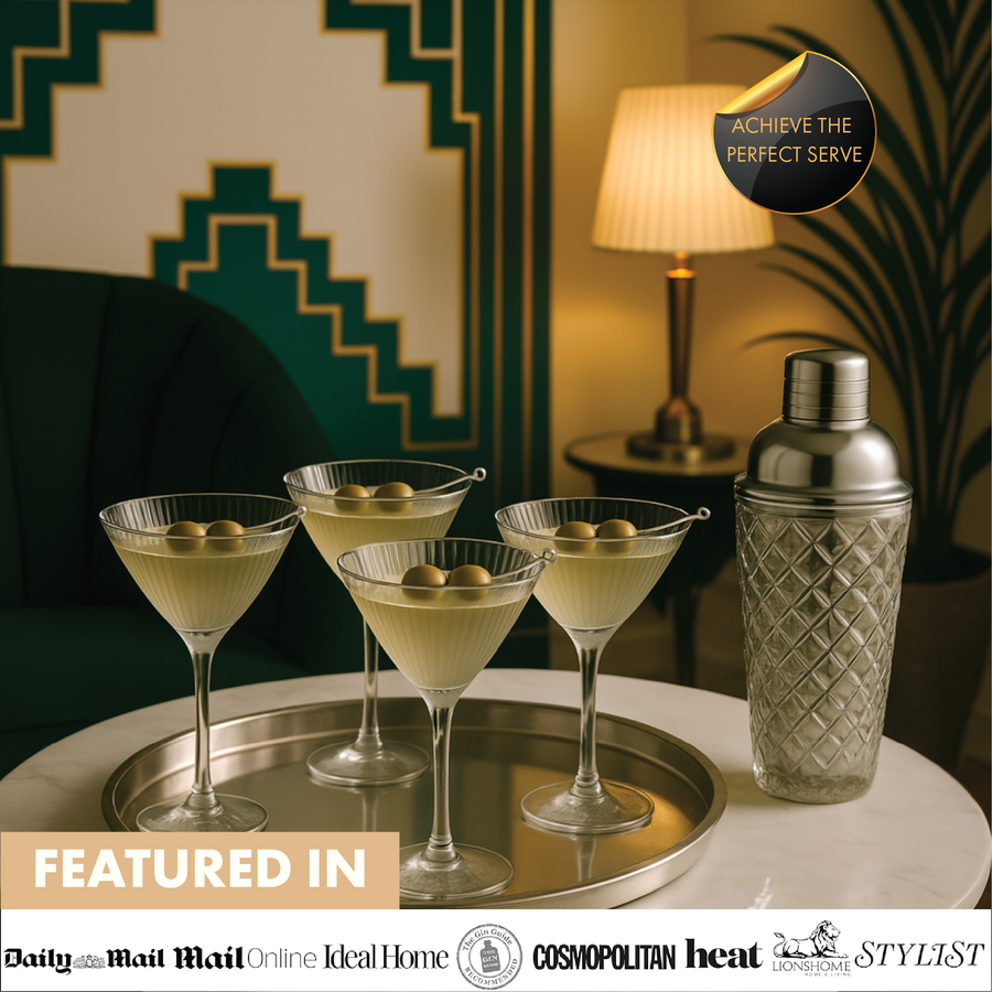 Lifestyle scene with four ribbed martini glasses and silver glass cocktail shaker on tray, elegant home bar setting.